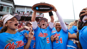 A group of Ole Miss softball players hoist a trophy after beating Arkansas in a super regional. 