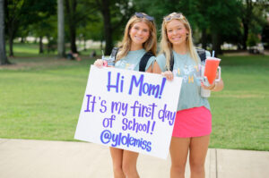 Students hold a sign announcing its their first day of school at the University of Mississippi. 